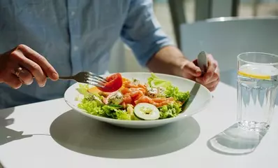 мужчина ест блюдо из овощей и морепродуктов