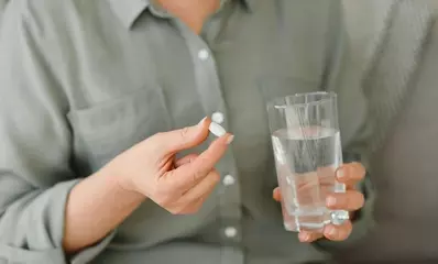 женщина с таблеткой и стаканом воды в руках